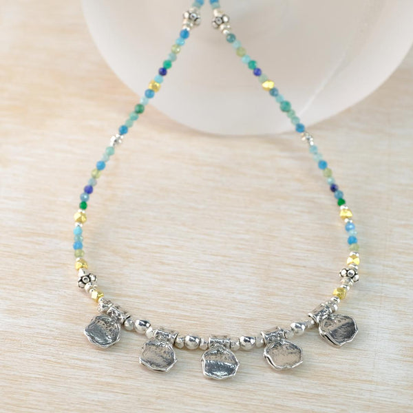 Necklace with colorful beads and silver pendants on a light wooden surface