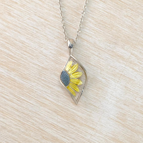 Sunflower pendant necklace on a light wood surface