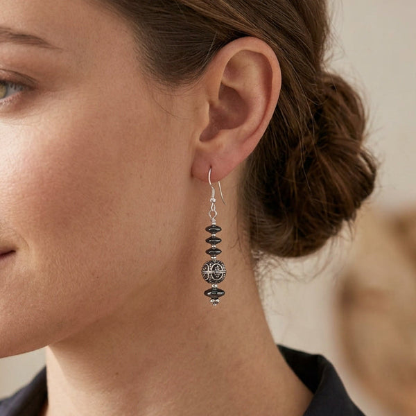 A pair of silver dangle earrings with dark gray beads and a central filigree sphere.