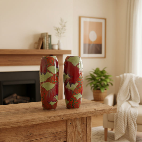 A pair of tall, glossy ceramic vases with abstract marbled patterns in red, light green, orange, and blue, set against a plain light gray background.