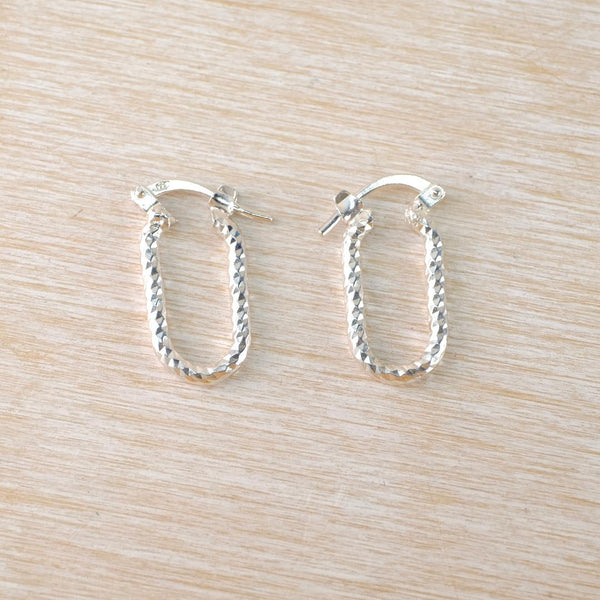 Pair of silver hoop earrings on a light wood surface