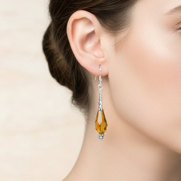 Pair of amber teardrop  glass bead earrings on a beige background