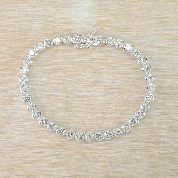 Silver bracelet with clear stones on a beige woven surface