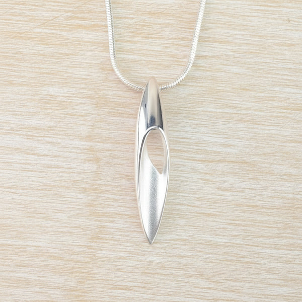 Silver pendant necklace on a light wood surface