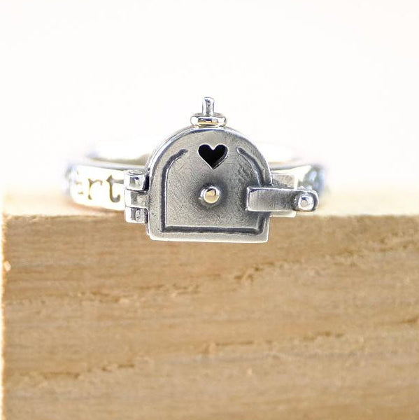 Silver ring with a heart design on a wooden block against a white background