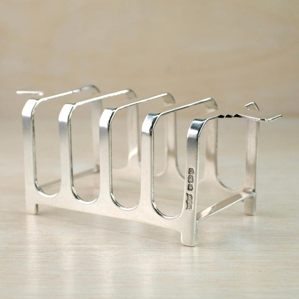 highly polished silver toast rack with spaces for four pieces of toast. A good clear visible hallmark on the side of one upright section. Overall rectangular in shape with geometric shapes on the two end sections to serve as handles very much in the Art Deco style