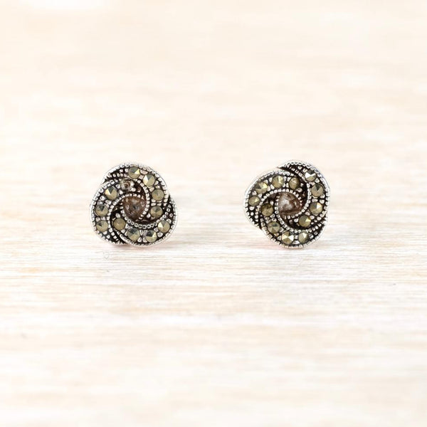 Pair of round knot earrings with intricate design on a light beige background