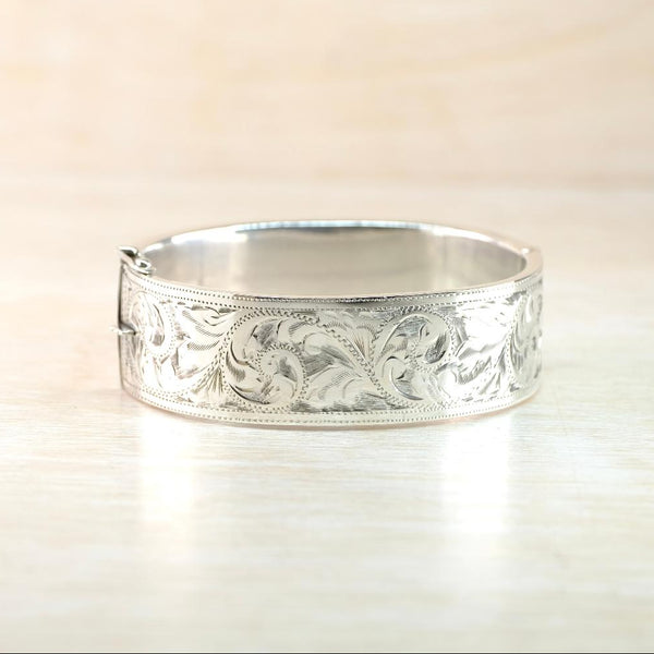 Silver bracelet with intricate leaf patterns on a light background