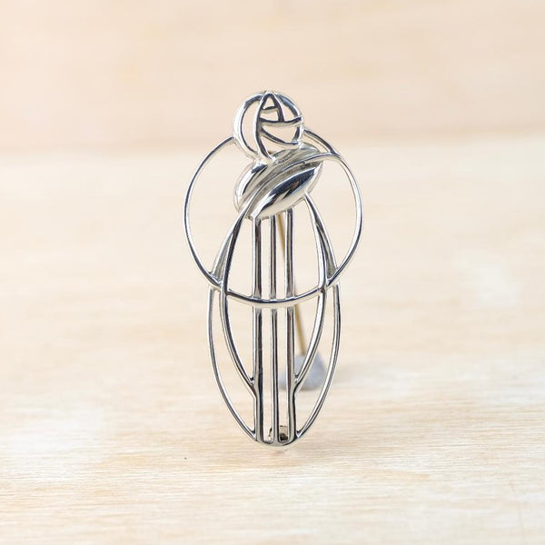 silver brooch with a leaf design on a beige background