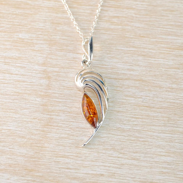 Silver pendant with an amber stone on a light wood background