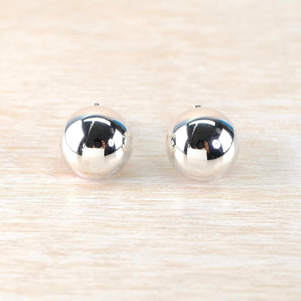 Pair of silver round domed earrings on a light wood background