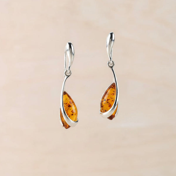 Pair of amber teardrop earrings against a beige background