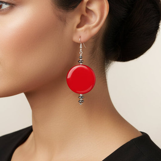 Red circular earrings with silver hooks on a beige background