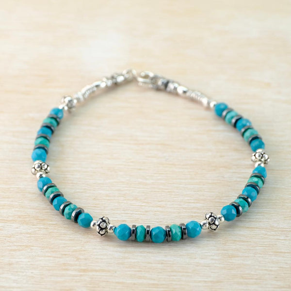 Turquoise beaded bracelet with silver accents on a light wood surface
