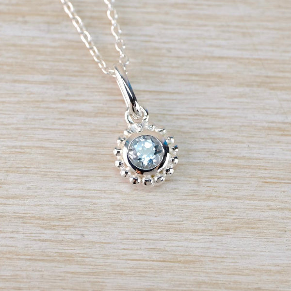 A pretty blue stone set in a circuar silver setting and suspended from a silver chain