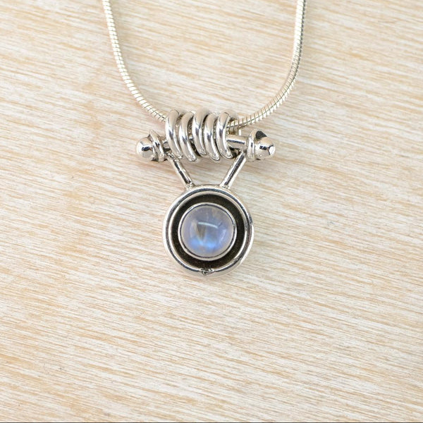 Silver necklace with a  moonstone pendant on a light wood surface