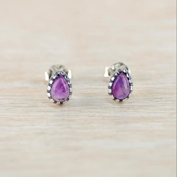 Pair of purple teardrop earrings on a light wood surface