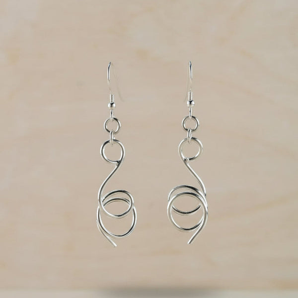 Silver spiral earrings against a beige background