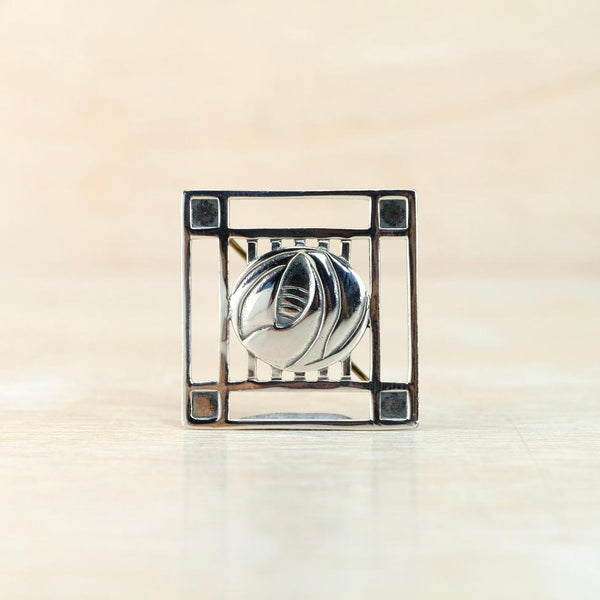 square broch wit a rose motif at the centre.