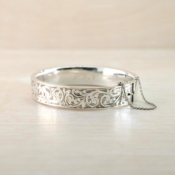 Silver bracelet with intricate  engraved design on a light beige background