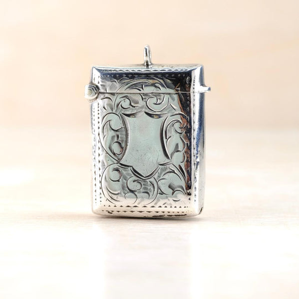 Silver decorative vesta case with intricate engraved patterns. It has a bale set centrally at the top.