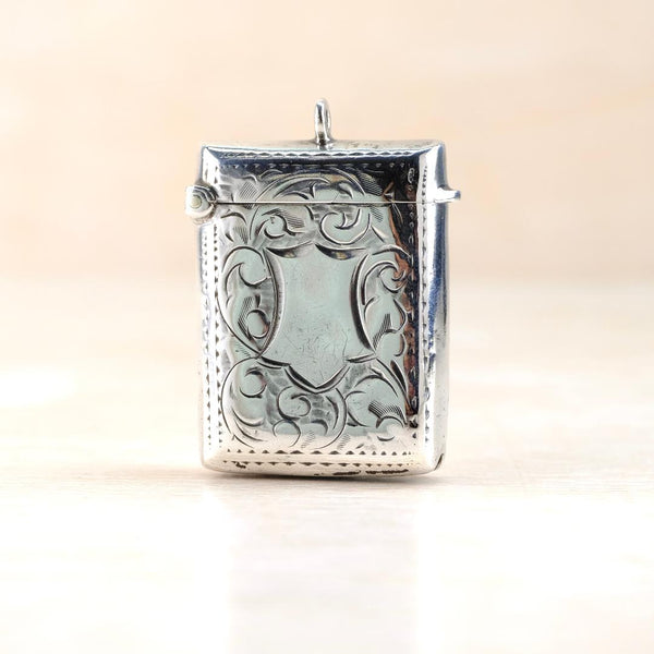Silver decorative vesta case with intricate engraved patterns. It has a bale set centrally at the top.