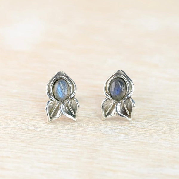 Silver earrings with gemstones on a beige surface