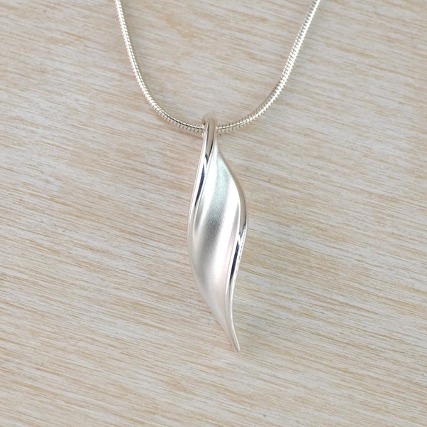 A silver pendant with a twisty leaf design attached to a snake chain, presented against a light background.
