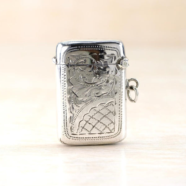 Engraved silver vesta case with hinged lid and bale set on one side.