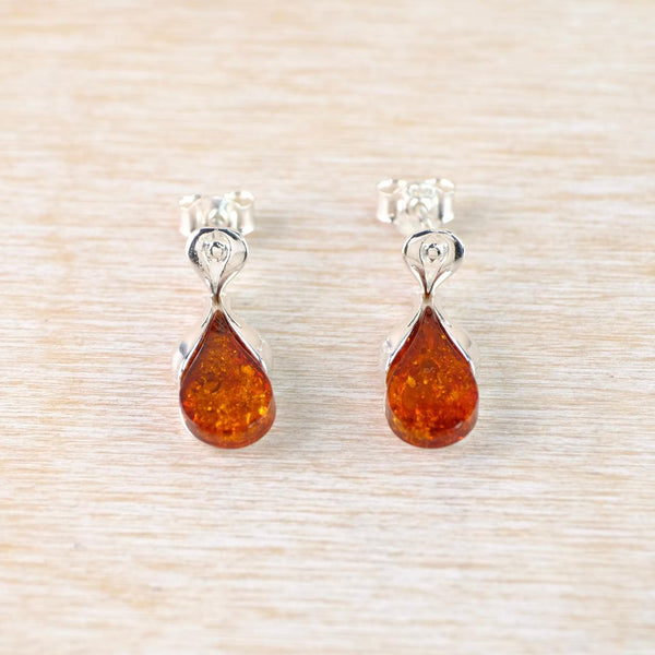 Pair of amber teardrop earrings on a light wood background