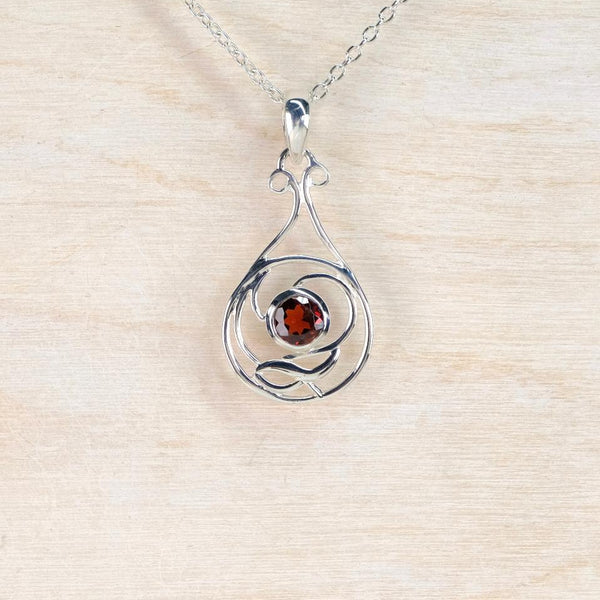 Silver pendant with a red gemstone on a beige background