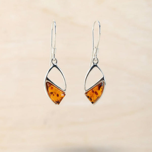 Pair of amber teardrop earrings against a beige background