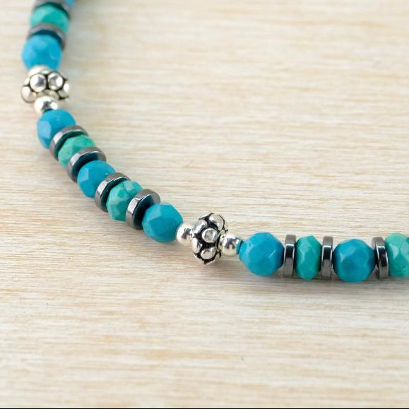Turquoise beaded bracelet with silver accents on a light wood surface