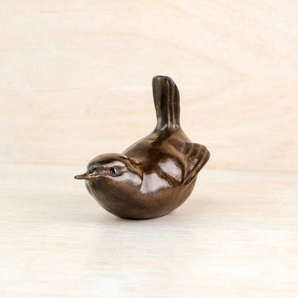 A small dark brown bird figurine, made of  bronze shown on a book
