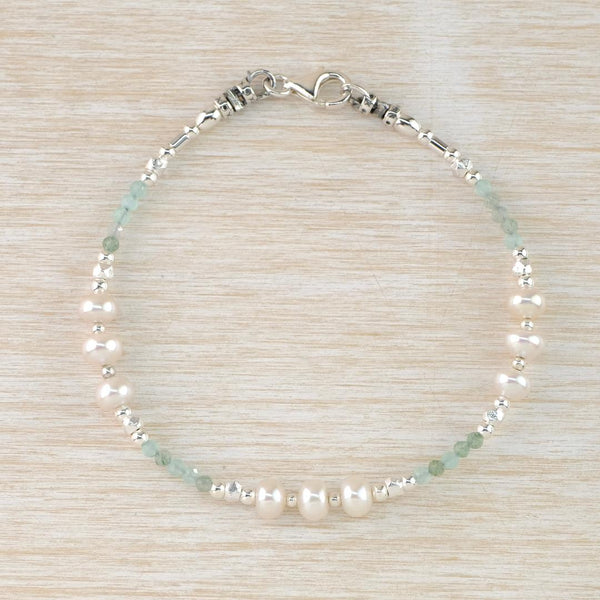 A delicate looking string of beads as a bracelet. Three sections of Three white freshwater pearls are interspersed with shiny silver beads and little aquamarine beads which have a lovely subtle sea green colour.