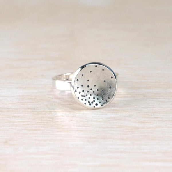 Silver ring with a textured surface on a light wood background