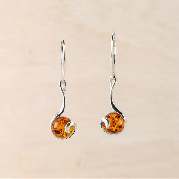 Pair of amber earrings against a beige background