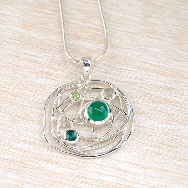Silver pendant with green gemstones set into a scribble effect wirework setting, and hanging from a silver chain