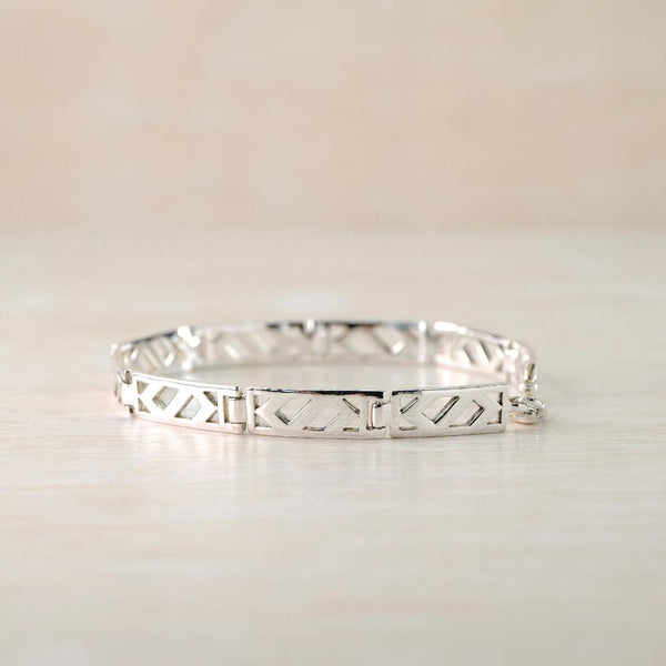 Silver bracelet with geometric design on a light beige background