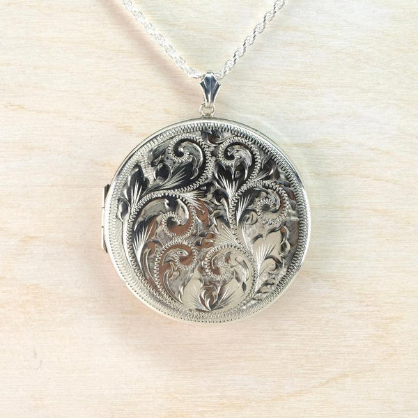 Silver locket with intricate designs on a light wood background