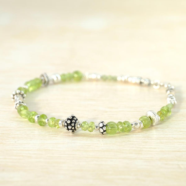 Beaded bracelet with green and silver beads on a light wooden surface