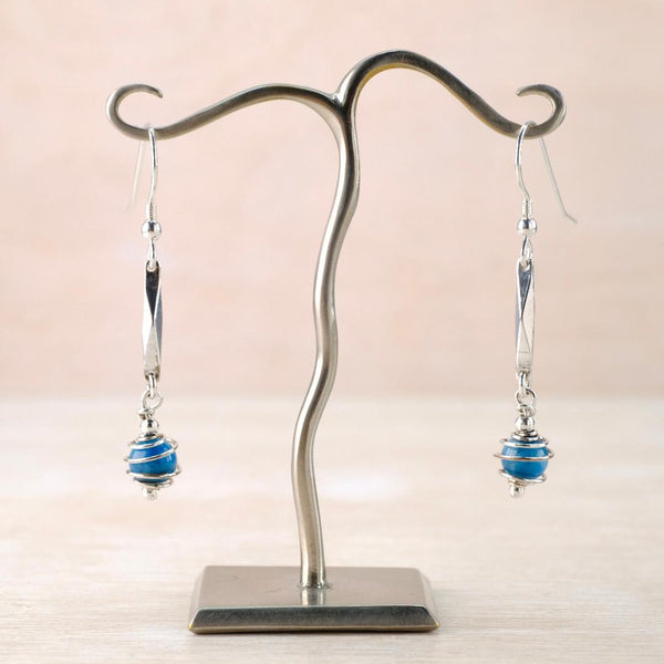 Dangly Silver earrings with blue beads wrapped in a wire spiral.