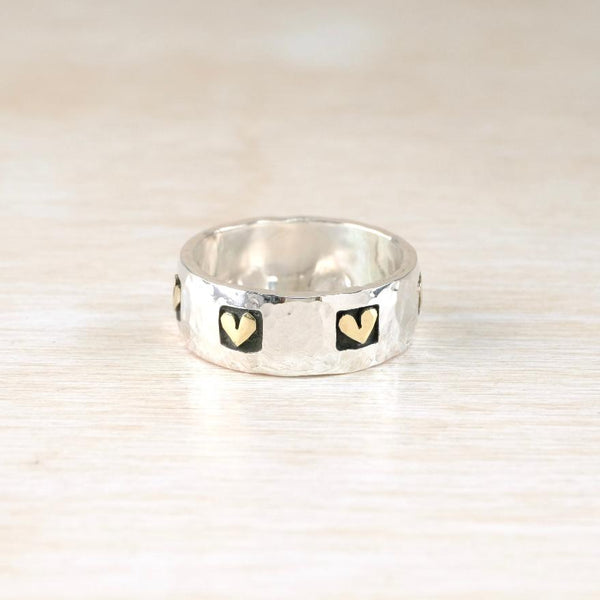 Silver ring with gold hearts on a beige background