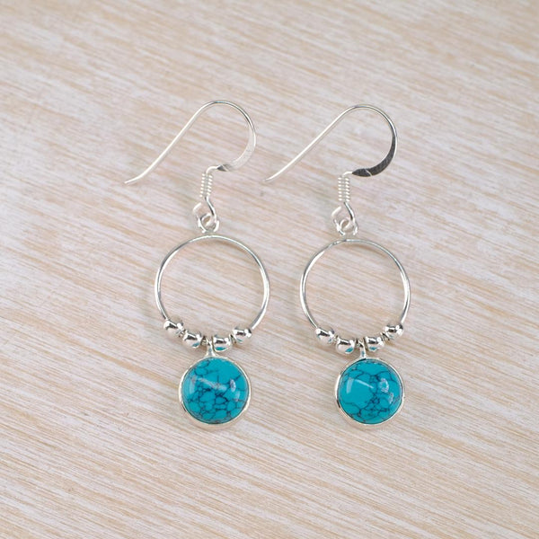 Silver earrings with turquoise stones dangling from silver rings