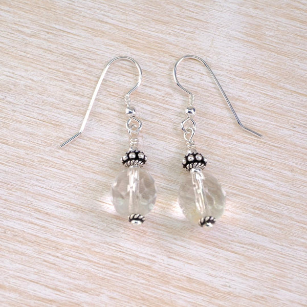 a pai of drop earrings with faceted clear beads and decorative silver beads