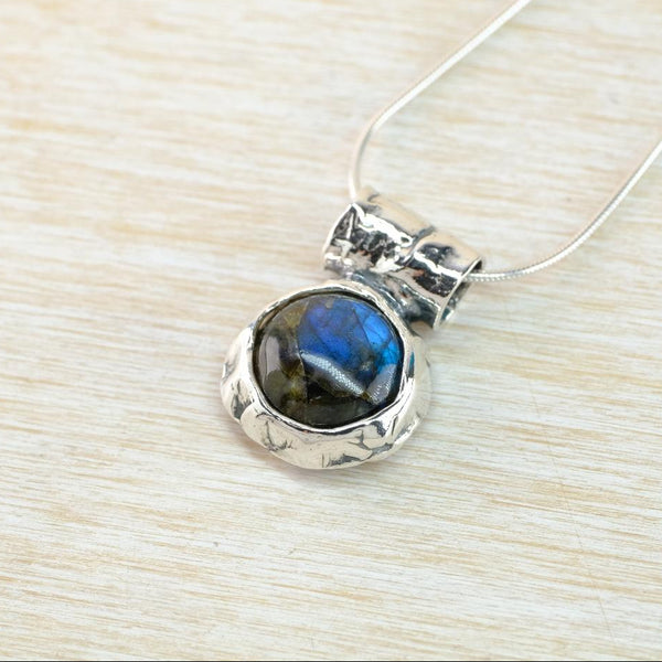 Silver pendant with a blue stone on a light wood surface