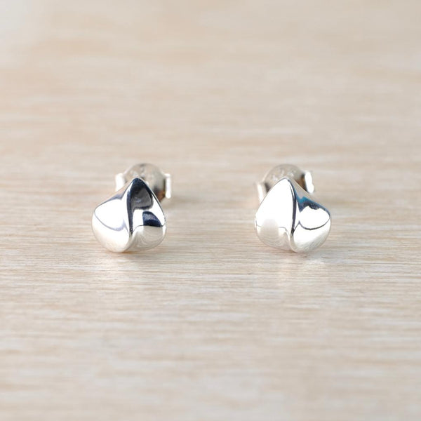 Pair of silver leaf-shaped earrings on a light wood background