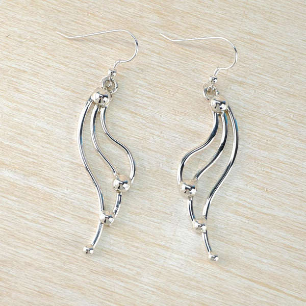 Silver earrings on a light wood surface