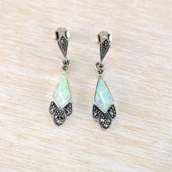 Pair of silver earrings with opal stones on a light wood background