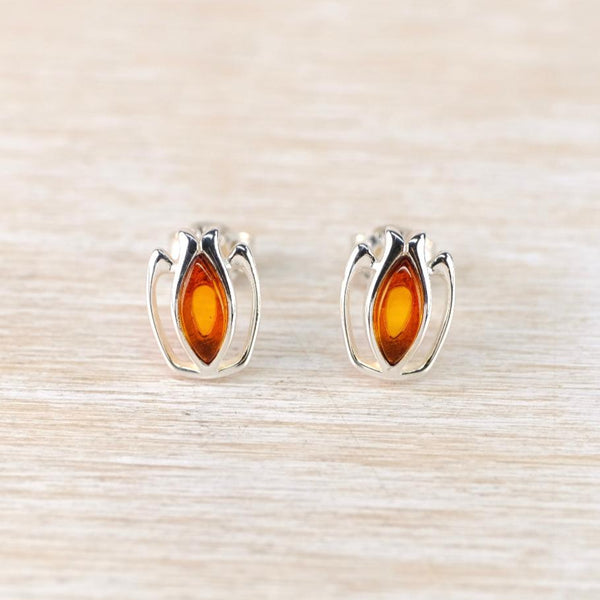 Pair of silver earrings with amber stones on a light wood background